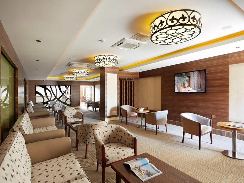 Modern lounge with comfortable armchairs, wooden walls, and decorative ceiling lights.