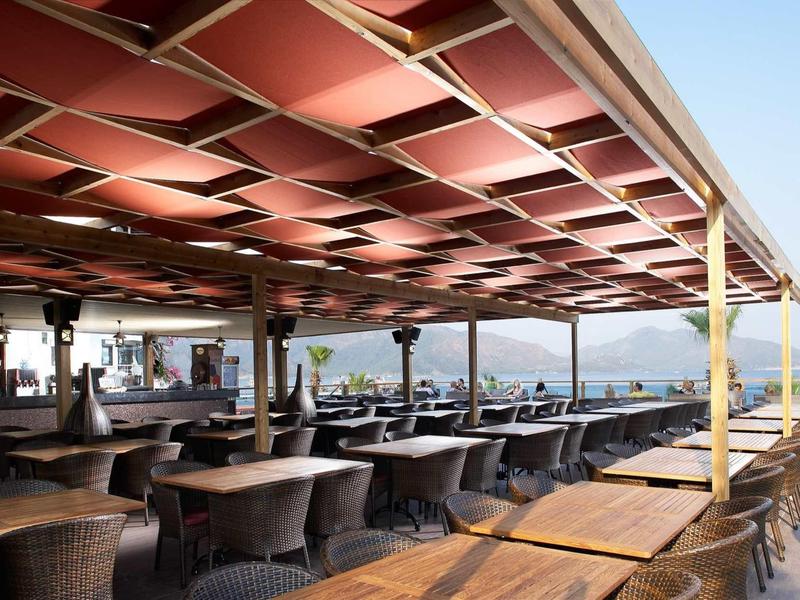 Covered terrace with many tables and chairs, mountain view in the background