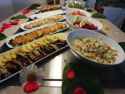 Buffet avec diverses entrées froides sur des assiettes et bols blancs, décoré de fleurs.