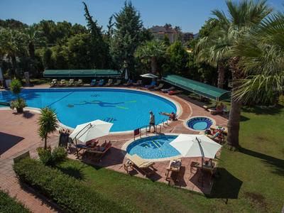 Pool area with lounge chairs and umbrellas in a tropical garden.