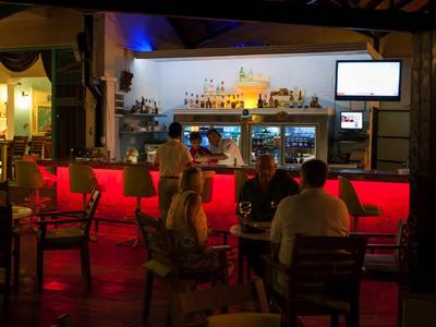 Bar avec éclairage rouge et clients dans une ambiance détendue en soirée.