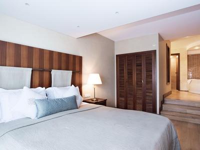 Modern hotel room with double bed, bedside lamp, and view into the bathroom.