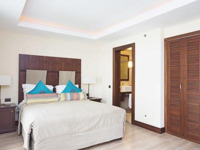 Chambre d'hôtel lumineuse avec lit double, deux tables de chevet, lampes et placard en bois.