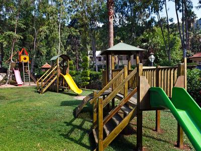 Aire de jeux extérieure pour enfants avec toboggans et structures d'escalade dans une zone boisée