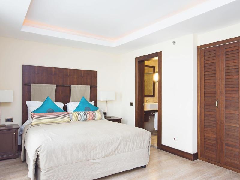 Chambre d'hôtel lumineuse avec lit double, deux tables de chevet, lampes et placard en bois.