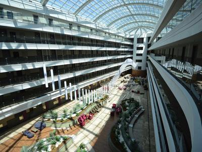 Großer heller Innenhof mit Glasdach, mehreren Stockwerken und dekorativen Pflanzen.