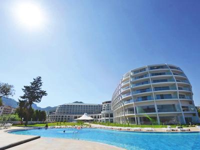 Moderner Hotelkomplex mit rundem Gebäude, Swimmingpool und klarem, blauem Himmel bei Sonnenschein.