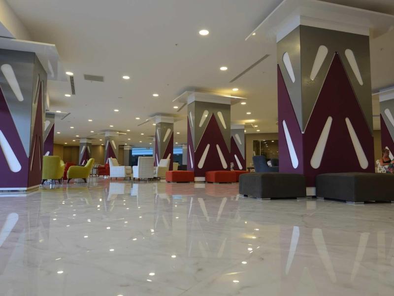 Großer, moderner Raum mit Marmorboden, bunten Sitzmöbeln und gestalteteten Säulen.