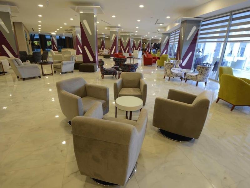 Großer, heller Warteraum mit hellen Sesseln, kleinen Tischen und glänzendem Marmorboden.