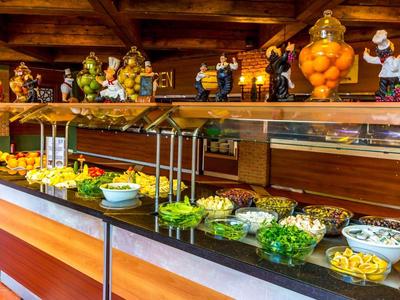Área de buffet con diversas ensaladas y productos frescos, detalles cálidos de madera en la habitación.