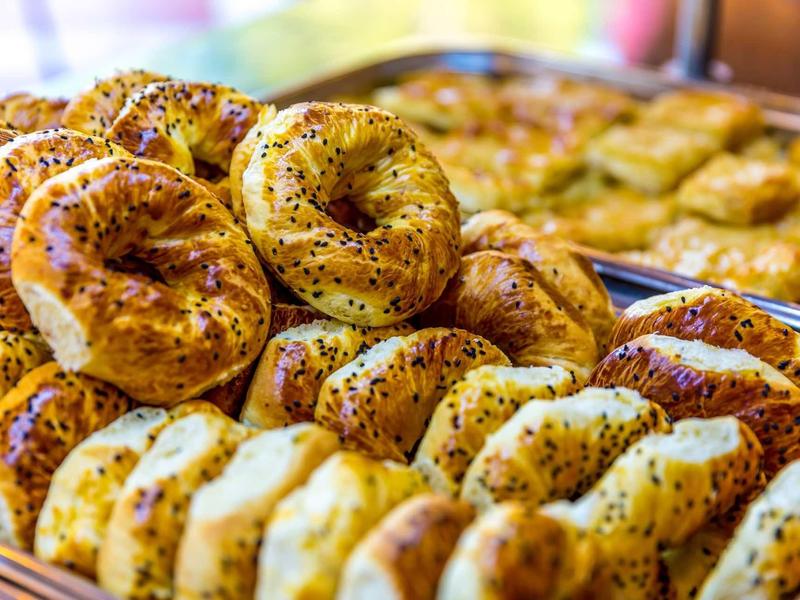 Variedad de bollería fresca con semillas de sésamo y amapola en una panadería, ideal para el desayuno del hotel.