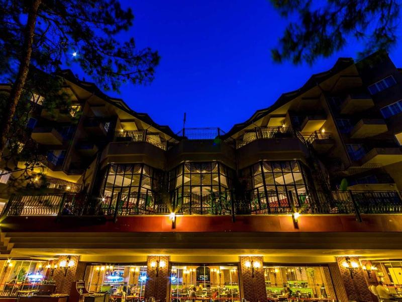Edificio de hotel iluminado con fachada de vidrio grande bajo el cielo nocturno oscuro.