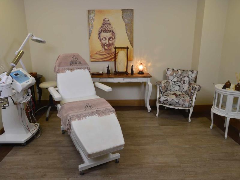 Sala de bienestar acogedora con camilla, equipo de tratamiento y cuadro decorativo de Buda.