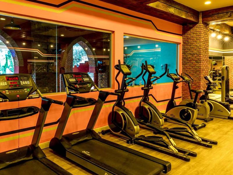Equipos de gimnasio modernos en una sala de fitness iluminada y colorida de un hotel.