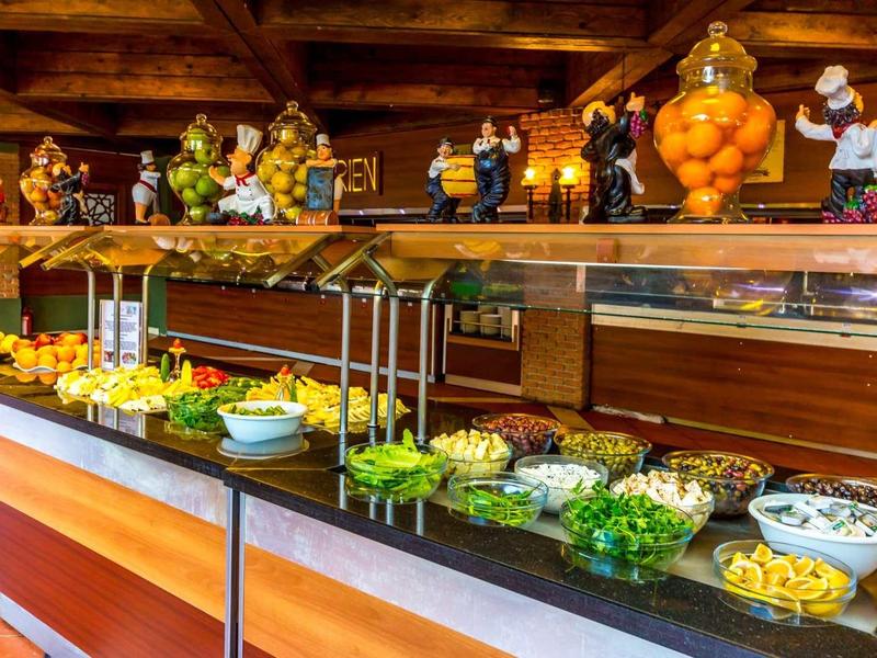 Área de buffet con diversas ensaladas y productos frescos, detalles cálidos de madera en la habitación.