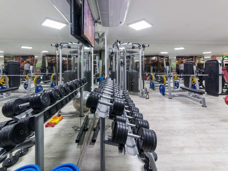 Palestra moderna con manubri, macchine per il fitness e specchi riflettenti in un hotel.