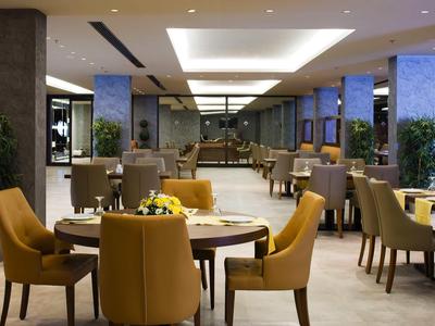 Nowoczesna restauracja z wygodnymi krzesłami i eleganckim oświetleniem w ciepłych tonach.