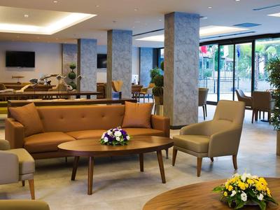 Moderne Lobby mit braunen Ledersofas, Holztischen, Pflanzen und großen Panoramafenstern.