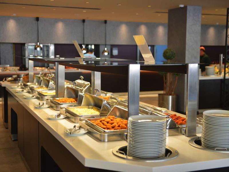 Buffet mit warmen Speisen, Tellern und modernem, hell beleuchtetem Raum.