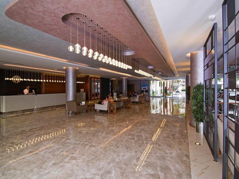 Moderner Hotel-Lobby mit glänzendem Marmorboden, langen Kronleuchtern und Glaswänden.