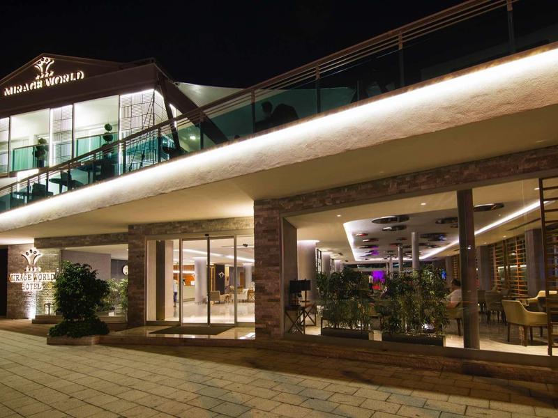 Modernes Gebäude mit großen Glasflächen, beleuchtet bei Nacht, mit offenem, einladendem Eingang.