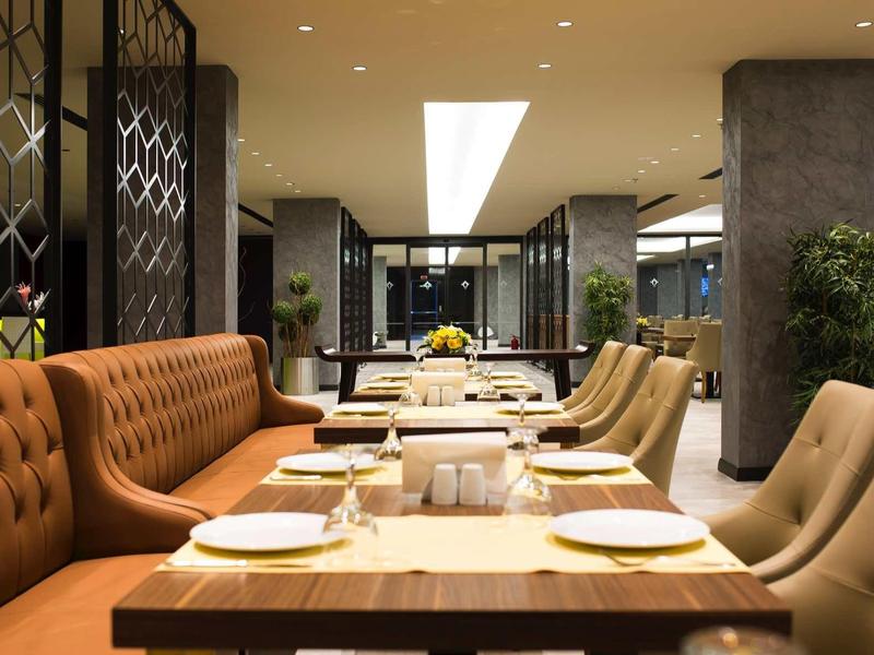 Moderne Restaurantinnenausstattung mit bequemen Polstersesseln in Beige und Braun, Tischen aus Holz.