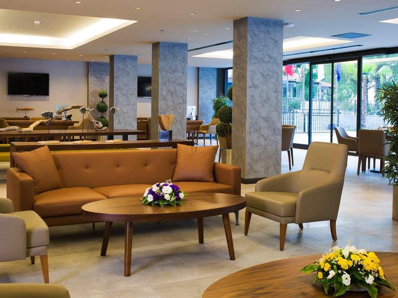 Moderne Lobby mit braunen Ledersofas, Holztischen, Pflanzen und großen Panoramafenstern.