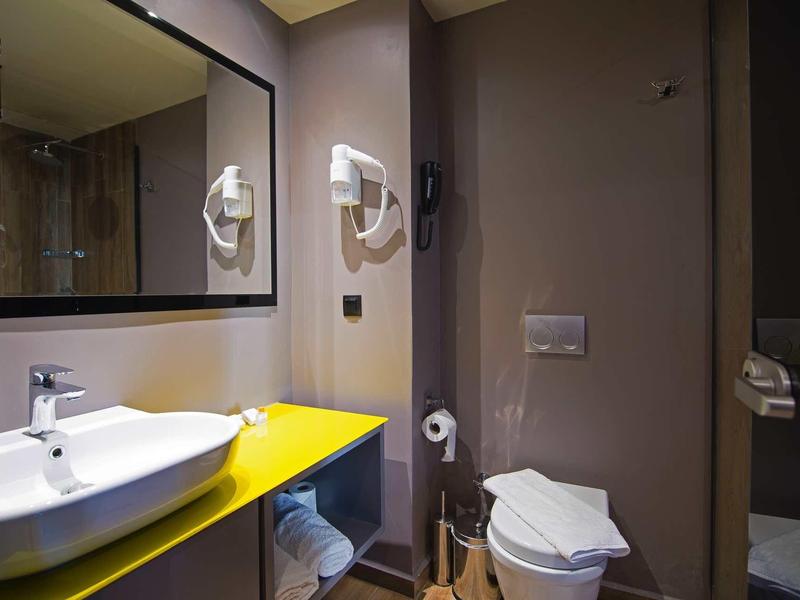 Kleines modernes Badezimmer mit weißem Waschbecken, gelber Arbeitsplatte und Toilettenbereich.