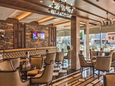 Przytulny hotelowy salon z wygodnymi fotelami, drewnianym sufitem i dużymi oknami.