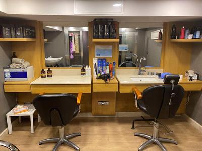 Friseursalon mit zwei schwarzen Stühlen, Spiegeln, Regalen mit Pflegeprodukten und Haarwerkzeugen.