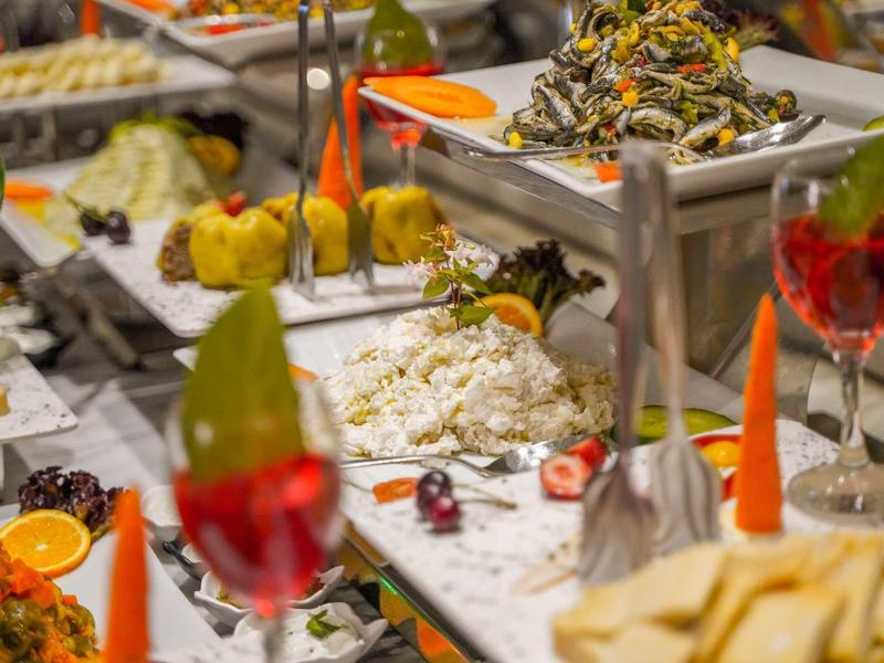 Buffet mit verschiedenen Speisen und farbenfrohen Getränken, dekoriert mit Kerzen.