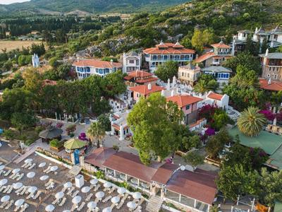 Luchtfoto van een resort met een zwembad, veel ligstoelen en omgeven door bomen en heuvels.