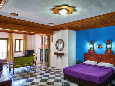 Przytulny pokój hotelowy z fioletowym łóżkiem, niebieską ścianą i częścią wypoczynkową.