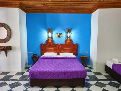 Przytulny pokój hotelowy z niebieską ścianą, drewnianym łóżkiem i kafelkową podłogą.