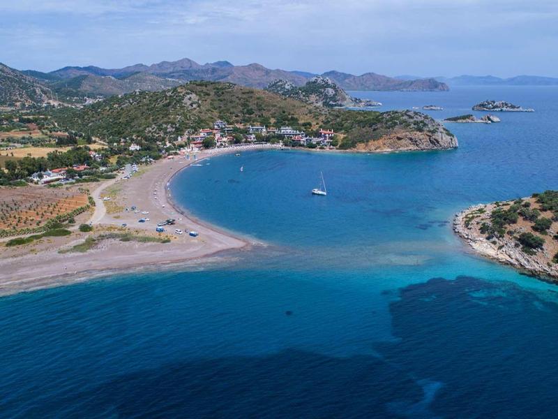 Zdjęcie z lotu ptaka zatoki przybrzeżnej z czystą, niebieską wodą i otaczającym krajobrazem.