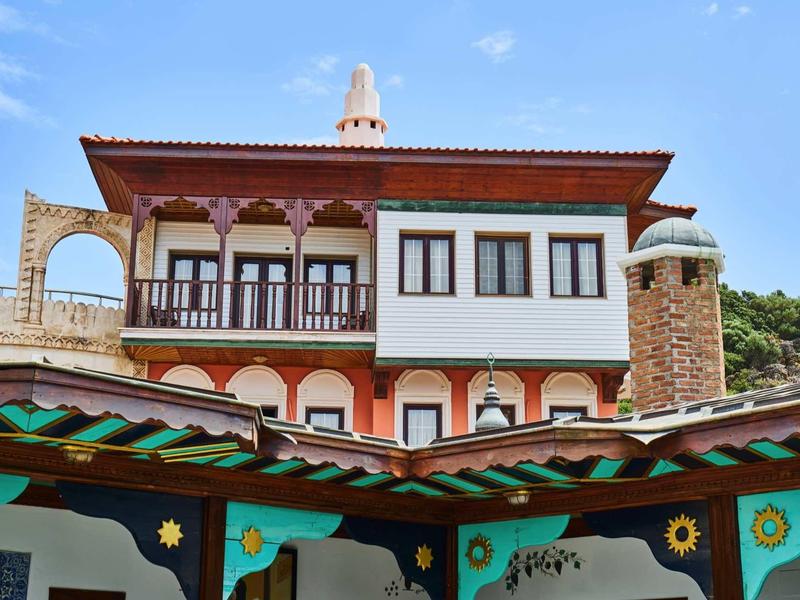 Tradycyjny budynek z rzeźbionymi drewnianymi detalami i kominami pod niebieskim niebem.