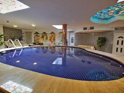 Überdachter Pool mit blauen Fliesen und dekorativen Wandbildern in einem Hotel.