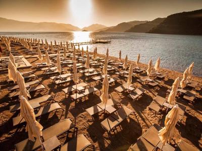 Strand met rijen ligstoelen en gesloten parasols bij zonsondergang.