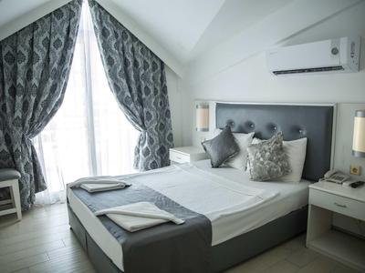 Modern hotelkamer met tweepersoonsbed, decoratieve kussens en grote raam met gordijnen