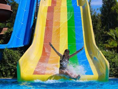 Enfant glissant sur un toboggan aquatique coloré dans une piscine par une journée ensoleillée.