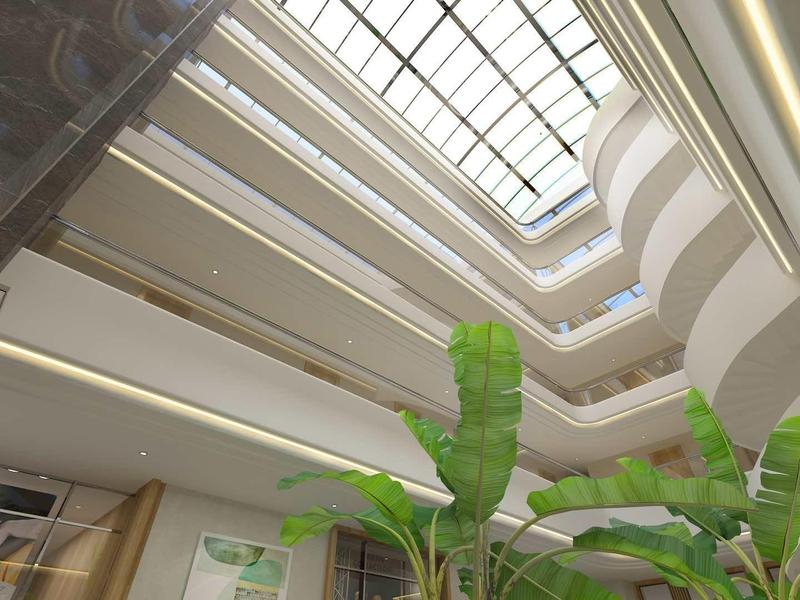 Blick nach oben in ein Atrium mit Glasdach, grünen Pflanzen und weißen Balkonen.