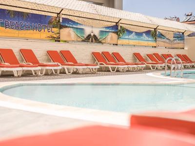 Prázdná oblast u bazénu s oranžovými lehátky před hotelem za slunečného dne