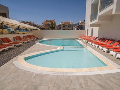 Modern outdoor pool with sun loungers in a hotel area under clear sky.