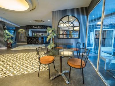 Moderní hotelová lounge s prosklenou stěnou, stolem a židlemi u recepce.