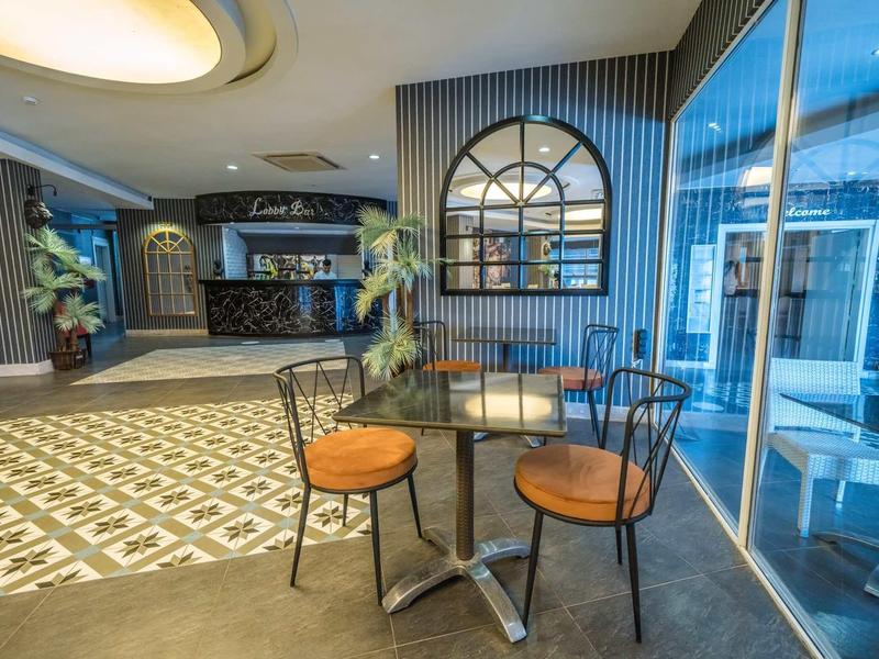 Moderní hotelová lounge s prosklenou stěnou, stolem a židlemi u recepce.