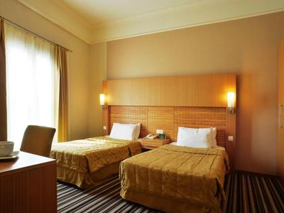 Hotelkamer met twee eenpersoonsbedden, houten meubels en warme verlichting.