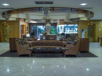 Elegancki hol hotelowy z skórzanymi sofami i dużą dekoracją kwiatową na środku.