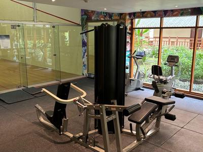 Fitnessraum mit Krafttrainingsgerät und großen Fenstern mit Blick ins Freie.