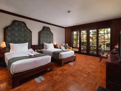 Cozy hotel room with two single beds, wooden floor, and large windows overlooking the garden.