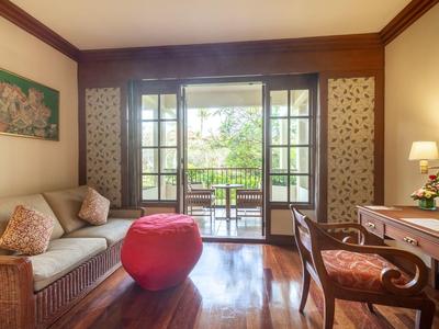 Cozy living area with sofa, red ottoman, and view of terrace and garden through large windows.